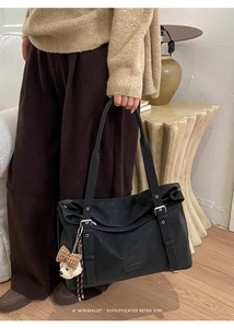 Détail d'un grand sac bandoulière noir vintage avec un joli charm d'ours en peluche