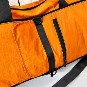 Detail shot of smooth black zipper and nylon fabric on an orange travel fitness bag