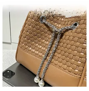 Detail of brown woven bucket bag with silver chain and white faux pearl accents