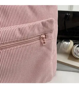 Detail of pink corduroy laptop backpack showing the side zipper pocket and soft fabric texture
