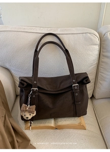 Détail d'un sac cabas rétro marron foncé en similicuir avec un pendentif ours en peluche