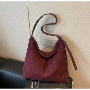 Detail of burgundy faux suede hobo bag featuring adjustable strap and premium texture