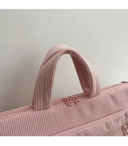 Detail of pink corduroy laptop bag featuring reinforced handles and dual metal zippers