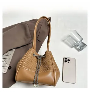 Detail of a brown woven bucket bag with silver chain drawstrings and pearl accents