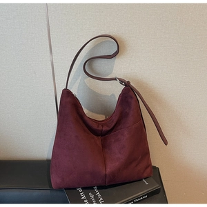 Detailed close-up of a burgundy suede tote bag featuring a front pocket and silver hardware
