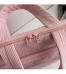 Close-up of pink corduroy tote bag showing dual metal zippers and ribbed fabric texture