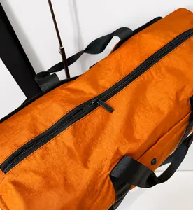 Close-up of smooth metal zipper and orange waterproof nylon fabric on sports bag