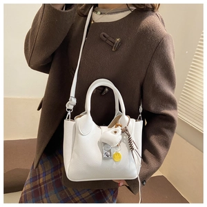 Detalle del bolso de cuero lichi blanco con cierre metálico y colgante de corazón