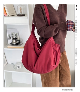 Close-up of a large burgundy crescent shoulder bag in soft matte nylon on a model