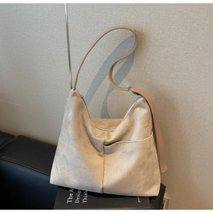 Close-up of beige suede hobo bag featuring external pocket and fine matte texture
