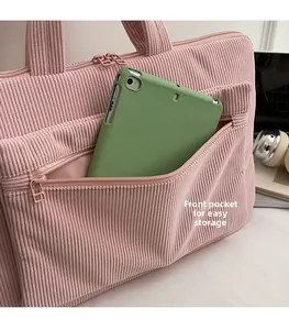 Pink corduroy laptop backpack detail showing a large front zip pocket for tablet storage