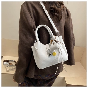 Detalle del bolso de mano blanco de cuero con cierre plateado y colgante de sonrisa