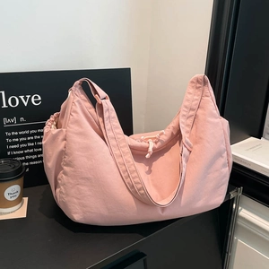 Pink nylon crossbody dumpling bag with wide shoulder strap and spacious drawstring interior