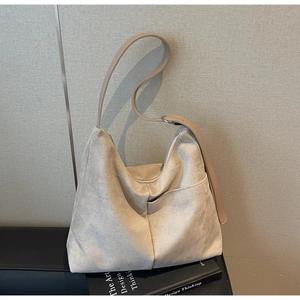 Detail view of beige suede tote bag with brown adjustable strap and side pocket