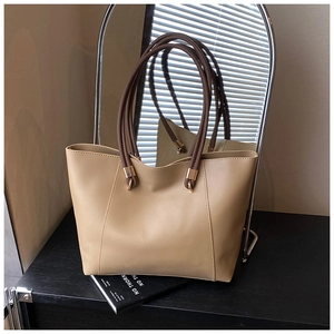 Detail of minimalist tote bag showing khaki leather texture and brown handle connection