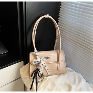 Close-up of beige PU leather shoulder bag with lace bow and silver metal ball charm