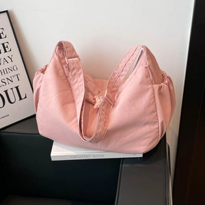 Detail view of pink nylon hobo bag featuring side drawstring pockets and wide strap