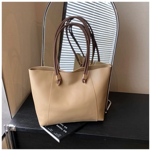 Detail of beige tote bag with brown handles and golden metallic hardware buckle