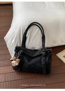 Détail du sac cabas en cuir noir avec boucles argentées et pendentif ours avec nœud écossais