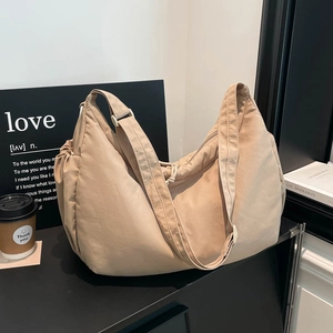 Detail of beige crescent hobo bag featuring drawstring closure and soft matte nylon texture