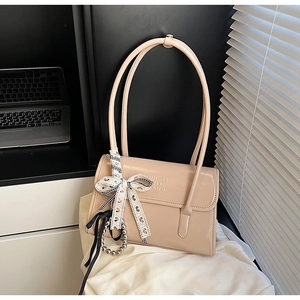 Detail of beige leather handbag featuring a lace bow and elegant pearl chain accent