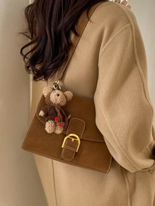 Bolso bandolera de ante marrón con hebilla dorada y colgante de oso en abrigo de lana