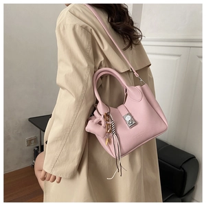 Bolso rosa textura lichi con cierre de reloj usado sobre un abrigo beige