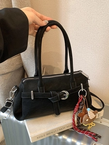 Vintage matte black top handle bag with crossbody strap and bear charm on silver suitcase