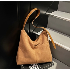 Detail of tan faux suede hobo bag with stitched seams and adjustable leather strap