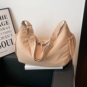 Minimalist beige nylon tote bag with crescent shape and adjustable shoulder strap