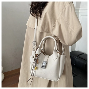 Bolso bandolera de cuero lichi blanco con cierre de reloj y detalle de borla tejida