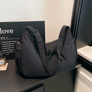 Close-up of black crossbody bag with adjustable wide strap and side drawstring pocket