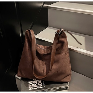 Close-up of dark brown suede tote bag with leather strap and silver metal buckle