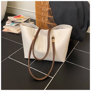 Detail of white tote bag with brown straps, gold hardware and matching inner pouch