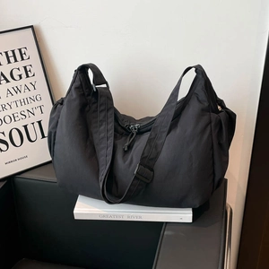 Detail of black nylon crescent bag with adjustable shoulder strap and metal zipper