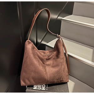 Close-up of brown suede tote bag featuring adjustable leather strap and front pocket