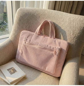 Détail du sac d'ordinateur en velours côtelé rose avec texture douce sur un canapé