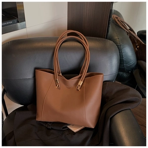 Detail of caramel brown tote bag with sleek gold hardware on black leather seat