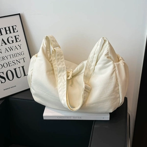 Detail of adjustable strap and buckle on a beige nylon crossbody crescent bag