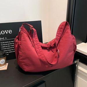 Detail of dark red nylon dumpling bag with adjustable drawstring and wide strap