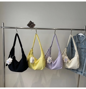 Row of colorful nylon dumpling bags with cute bunny pendants on a minimalist rack