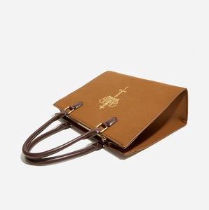 Detailed side view of brown suede tote bag featuring a golden crown and sword emblem