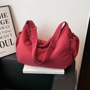 Detail of burgundy crossbody dumpling bag featuring adjustable strap and side pockets