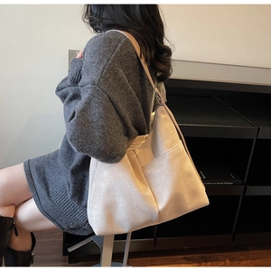 Detail of large cream suede tote bag showing side pocket and wide shoulder strap