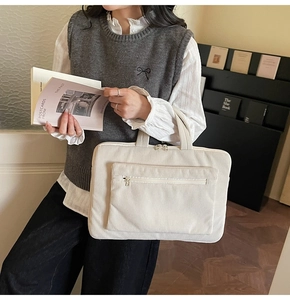 Close-up of beige corduroy laptop tote bag with reinforced handles and metal zipper details