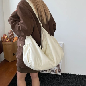 Detail of a large cream nylon crossbody dumpling bag showing the soft satin texture