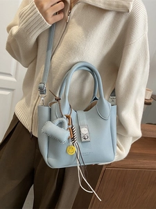 Bolso tipo cubo en cuero azul cielo con cierre de giro plateado y colgante decorativo