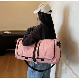 Detailed view of pink foldable gym bag with black straps and side zipper pockets