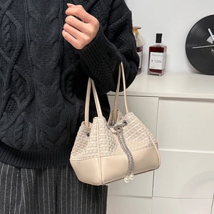 Détail du sac seau tressé beige avec chaîne argentée et ornements de perles