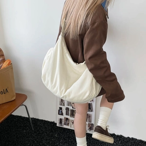 Minimalist cream shoulder bag with soft textured cloud shape worn by model in casual scene